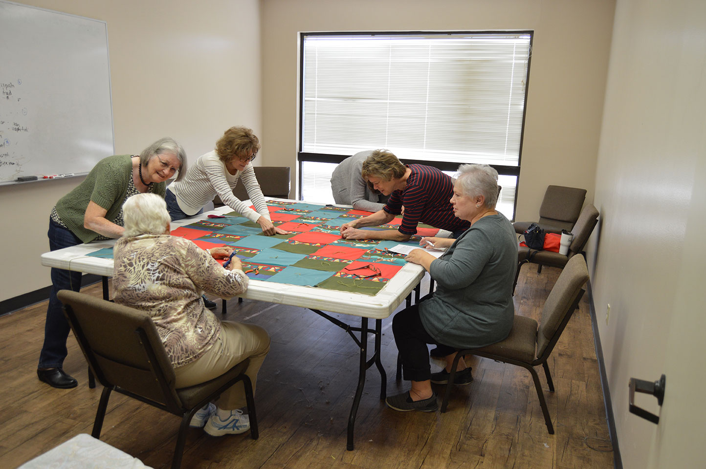 Women sitting and making a quilt.